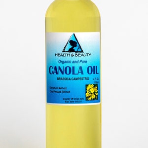 May include: A clear glass bottle with a white cap filled with yellow canola oil. The label is blue and white and reads "HEALTH & BEAUTY Organic and Pure CANOLA OIL BRASSICA CAMPESTRIS 4 FL. Oz 118 ml Extraction Method: Cold Pressed Refined Country Of Origin Italy Exp. date"