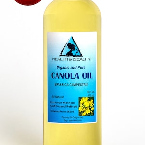 May include: A clear glass bottle of organic and pure canola oil, labeled "Health & Beauty" with a blue triangle logo. The bottle contains 16 fluid ounces (473 ml) and is labeled "All Natural" with the extraction method, "Cold Pressed Refined". The label also states that the oil is obtained from seeds and the country of origin is Italy.