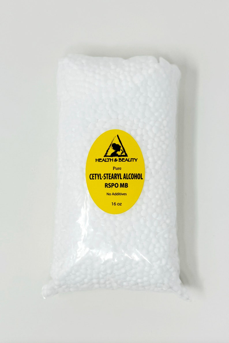 May include: A clear plastic bag filled with white beads. The bag has a yellow label with a black triangle and the text "HEALTH & BEAUTY Pure CETYL-STEARYL ALCOHOL RSPO MB No Additives 16 oz".