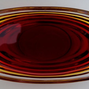 May include: A clear glass bowl with a red liquid inside. The bowl has a rounded shape and a smooth, shiny surface.