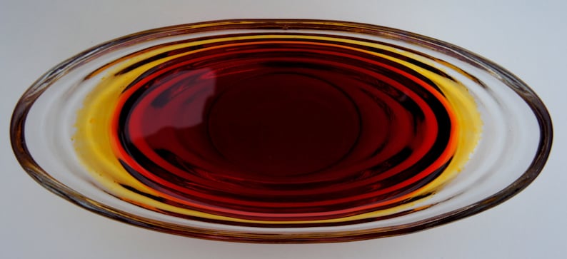 May include: A clear glass bowl with a red liquid inside. The bowl has a rounded shape and a smooth, shiny surface.
