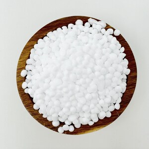 May include: A wooden bowl filled with white, round, uniform-sized beads. The beads are smooth and appear to be made of plastic or ceramic.