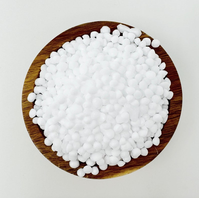 May include: A wooden bowl filled with white, round, uniform-sized beads. The beads are smooth and appear to be made of plastic or ceramic.