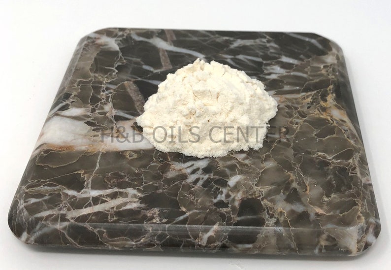 May include: A close-up of a white powder on a brown marble surface. The powder is in a small pile and is slightly rounded. The text "H&B OILS CENTER" is visible on the surface.