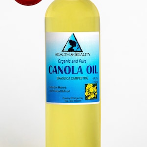 May include: A clear glass bottle with a white cap containing 4 fluid ounces (118 ml) of organic and pure Canola Oil. The label is blue with white text and a graphic of a canola flower. The label reads "Health & Beauty, Organic and Pure, Canola Oil, Brassica Campestris, 4 Fl. Oz, 118 ml, Extraction Method: Cold Pressed Refined, Country of Origin Italy, Exp. date".