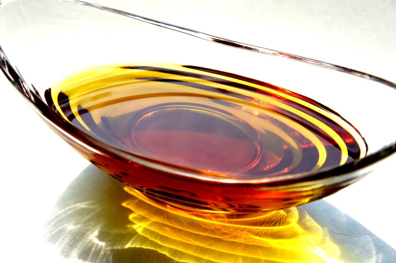 May include: A clear glass bowl filled with a golden brown liquid, creating concentric circles of light and dark shades.