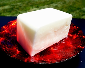 May include: A white rectangular block of soap sits on a red swirl patterned plate.