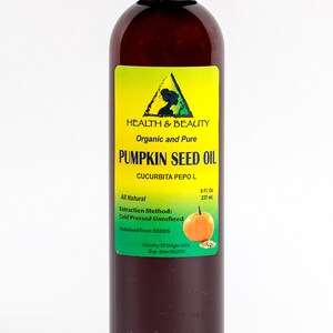 May include: A brown glass bottle of organic and pure pumpkin seed oil. The label is green and yellow with the text "HEALTH & BEAUTY", "Organic and Pure", "PUMPKIN SEED OIL", "CUCURBITA PEPO L", "All Natural", "Extraction Method: Cold Pressed Unrefined", "Obtained from SEEDS", "Country Of Origin USA", and "Exp. date". The bottle contains 8 fluid ounces (237 ml) of oil.