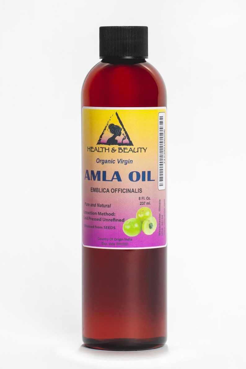 May include: A brown glass bottle with a black cap containing organic virgin Amla oil. The label is yellow with a black triangle and the text "HEALTH & BEAUTY" and "AMLA OIL". The label also includes the text "EMBLICA OFFICINALIS", "Pure and Natural", "8 Fl. Oz. 237 ml.", "Extraction Method: Cold Pressed Unrefined", "obtained from SEEDS", "Country Of Origin India", and "Exp. date". There are green Amla berries on the label.