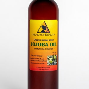 Puede incluir: Una botella de vidrio marr&oacute;n de aceite de jojoba virgen dorado org&aacute;nico. La etiqueta es amarilla con un tri&aacute;ngulo negro y las palabras "HEALTH & BEAUTY" y "JOJOBA OIL". La botella es de 8 onzas l&iacute;quidas o 237 mililitros.
