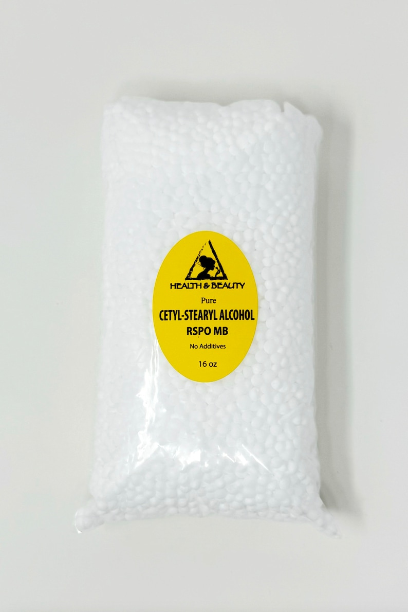May include: A clear plastic bag filled with white beads. The bag has a yellow label with a black triangle and the text "HEALTH & BEAUTY Pure CETYL-STEARYL ALCOHOL RSPO MB No Additives 16 oz".