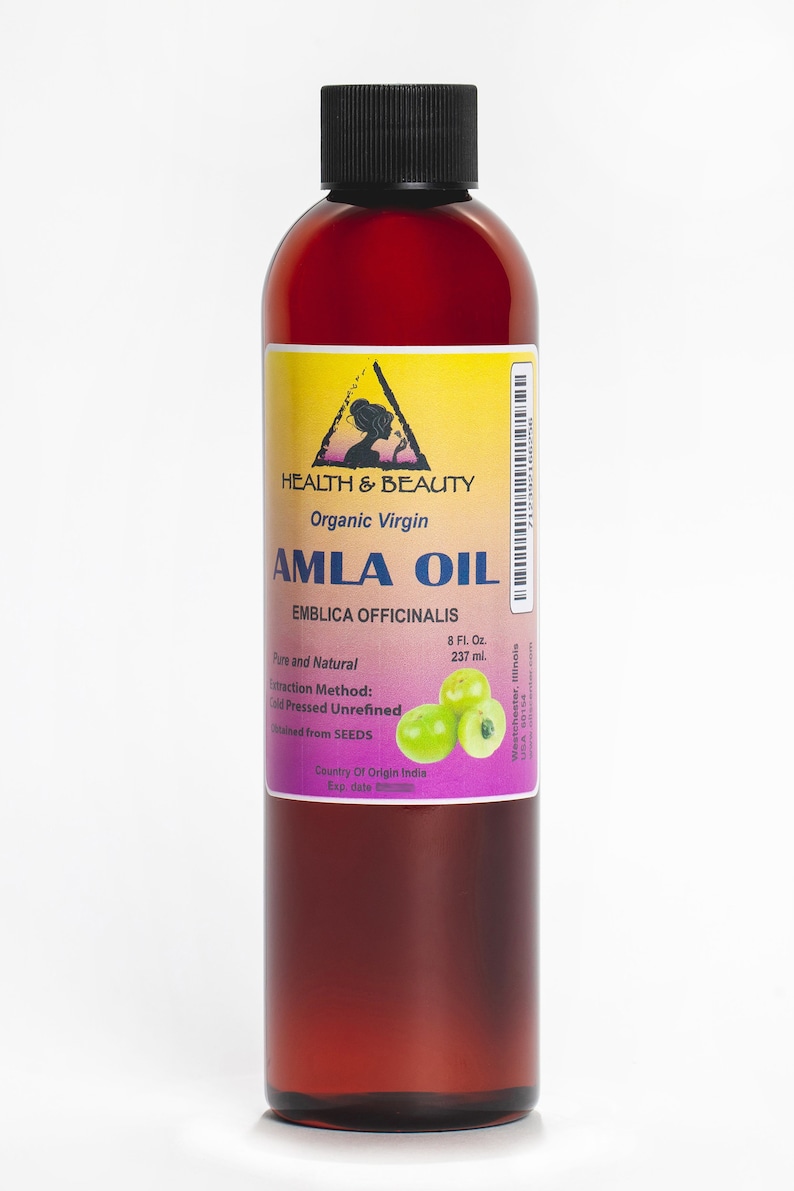 May include: A brown glass bottle with a black cap containing organic virgin Amla oil. The label is yellow with a black triangle and the text "HEALTH & BEAUTY" and "AMLA OIL". The label also includes the text "EMBLICA OFFICINALIS", "Pure and Natural", "8 Fl. Oz. 237 ml.", "Extraction Method: Cold Pressed Unrefined", "obtained from SEEDS", "Country Of Origin India", and "Exp. date". There are green Amla berries on the label.