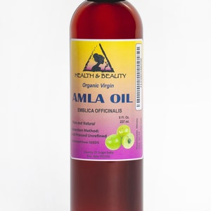 May include: A brown glass bottle with a black cap containing organic virgin Amla oil. The label is yellow with a black triangle and the text "HEALTH & BEAUTY" and "AMLA OIL". The label also includes the text "EMBLICA OFFICINALIS", "Pure and Natural", "8 Fl. Oz. 237 ml.", "Extraction Method: Cold Pressed Unrefined", "obtained from SEEDS", "Country Of Origin India", and "Exp. date". There are green Amla berries on the label.