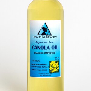 May include: A clear glass bottle of organic and pure canola oil, labeled "HEALTH & BEAUTY CANOLA OIL BRASSICA CAMPESTRIS" with a blue and white label. The bottle contains 16 fluid ounces (473 ml) and is made with cold pressed refined oil obtained from seeds. The country of origin is Italy.