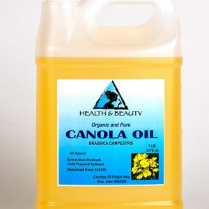 May include: A gallon jug of organic and pure canola oil, labeled "Health & Beauty" with the text "Canola Oil" and "Brassica Campestris". The label also states "All Natural", "Extraction Method: Cold Pressed Refined", "Obtained from SEEDS", "Country of Origin Italy", and "Exp. date". The jug is filled with yellow oil and has a white cap.