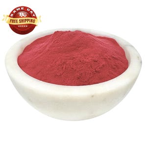 May include: A white bowl filled with a vibrant red powder. The powder is finely ground and has a smooth texture.
