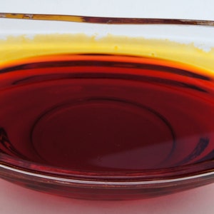 May include: A clear glass bowl filled with a dark red liquid with a thin layer of yellow liquid on top.