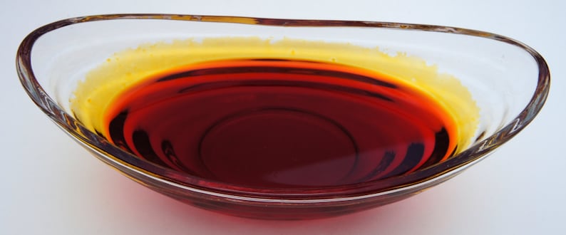 May include: A clear glass bowl filled with a dark red liquid with a thin layer of yellow liquid on top.