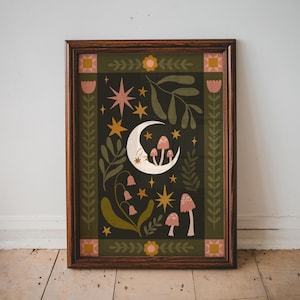 May include: A framed art print with a whimsical design. It features a crescent moon, mushrooms, stars, and floral elements in green, pink, and gold. The artwork is set against a dark background and framed in dark wood.