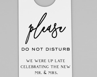 May include: White hotel door hanger with a black cursive "please" and the text "DO NOT DISTURB". The text "WE WERE UP LATE CELEBRATING THE NEW MR. & MRS. Davidson" is also printed in black.