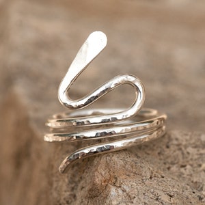 Op de afbeelding: Een zilveren ring met een gehamerde afwerking, in de vorm van een slang met een opgeheven kop.