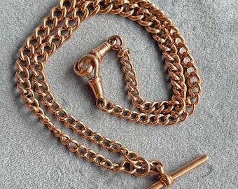 Könnte beinhalten: Eine goldfarbene Kette mit einem T-Bar-Verschluss. Die Kette besteht aus zwei Reihen von miteinander verbundenen Kreisen.