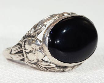 May include: A silver ring with a black oval gemstone set in a floral design.