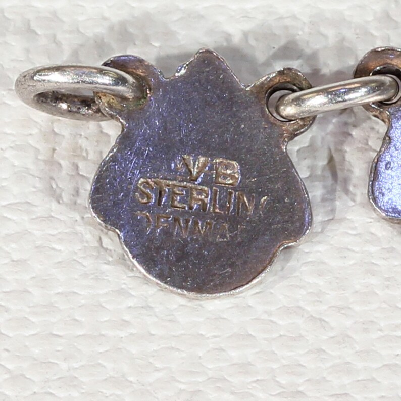 Pu&ograve; includere: Primo piano di un ciondolo d'argento con la scritta "VB Sterling Denmark" sul retro.