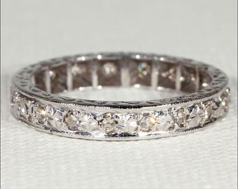 Könnte beinhalten: Ein silberner Ewigkeitsring mit einer Reihe kleiner Diamanten, die in einem zarten, milgrain-verzierten Design gefasst sind.
