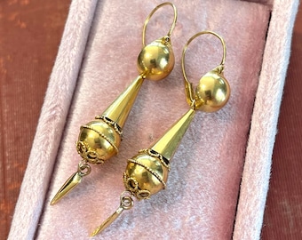 May include: A pair of gold dangle earrings with a teardrop-shaped design. The earrings have a delicate, intricate design and are perfect for adding a touch of elegance to any outfit.