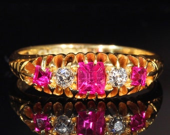 May include: A gold ring with three pink gemstones and three small diamonds. The ring is set in a delicate, ornate design.