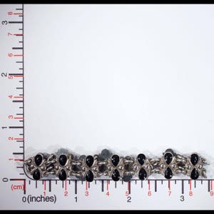 Pu&ograve; includere: Un braccialetto d'argento con pietre nere, che misura circa 19 cm di lunghezza.
