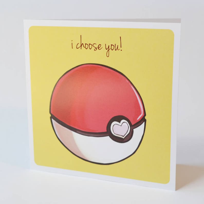 Puede incluir: Una tarjeta amarilla con el texto "i choose you!" y una Pok&eacute; Ball roja y blanca con un coraz&oacute;n rosa.