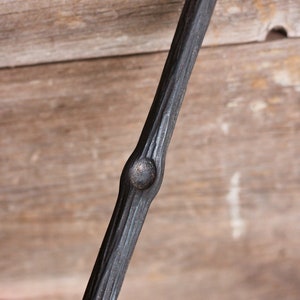 May include: A black metal handrail with a textured, wood-like finish. The handrail has a single knot in the center.