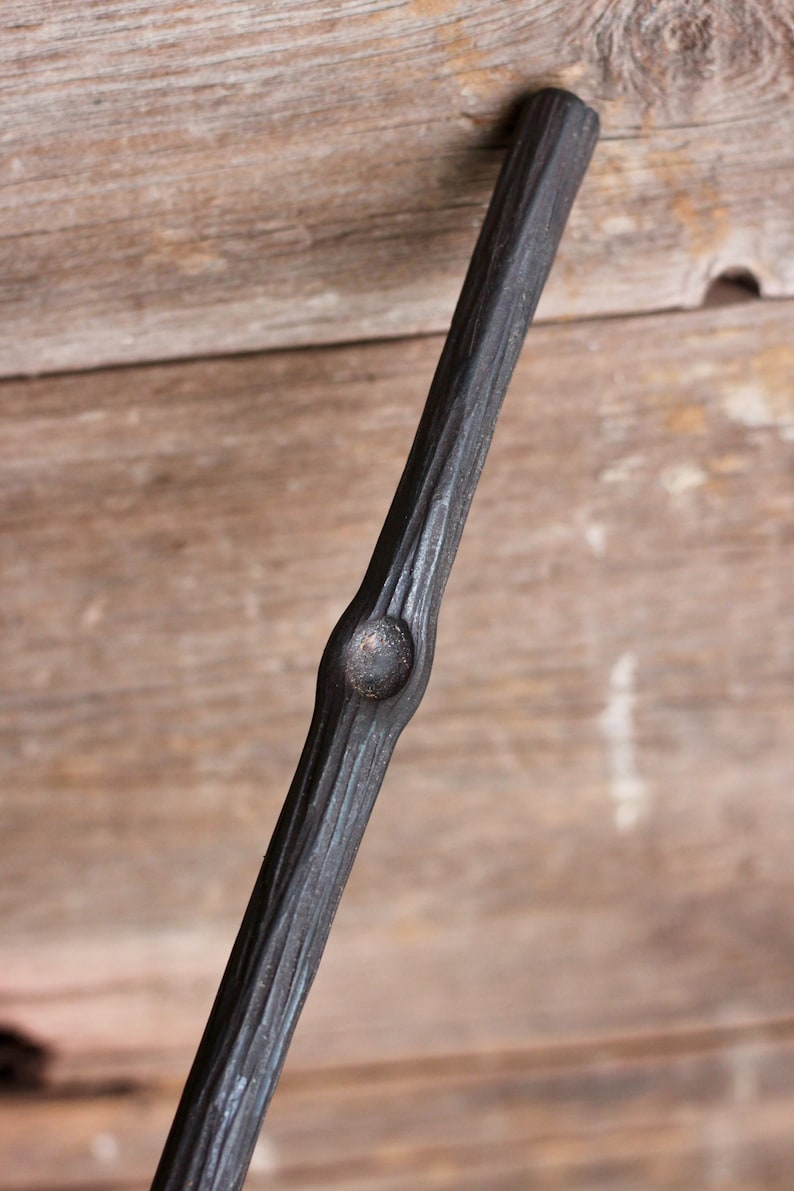 May include: A black metal handrail with a textured, wood-like finish. The handrail has a single knot in the center.