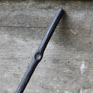 May include: A black metal rod with a textured surface and a round knob in the middle.