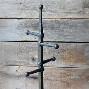 May include: A black metal coat rack with five hooks. The rack is made of wrought iron and has a rustic, industrial look.