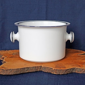 May include: White ceramic serving bowl with two handles and a blue rim. The bowl is sitting on a wooden surface.