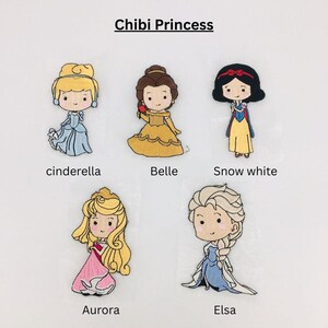 以下が含まれることがあります： ディズニーのプリンセス、シンデレラ、ベル、白雪姫、オーロラ、エルサのちびバージョンが刺繍されたパッチ。各パッチは、象徴的な衣装を着たプリンセスを特徴とし、プリンセスの名前が下にあります。「Chibi Princess」というテキストが上部にあります。