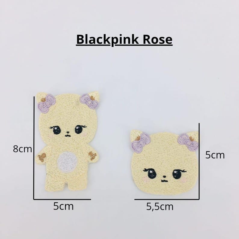 May include: Two embroidered iron-on patches featuring a cartoon bear with purple flowers on its head. The larger patch is 8 cm tall and 5 cm wide. The smaller patch is 5 cm wide and 5.5 cm tall. Both patches are yellow with a white face and black eyes.