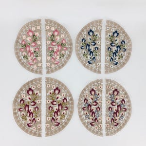 May include: Four pairs of embroidered fabric appliques in the shape of half circles. Each applique features a floral design with different color combinations: pink and green, blue and white, burgundy and green, and blue and white.