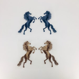 May include: Four embroidered iron-on patches of rearing horses. Two are blue and two are brown.