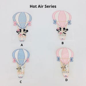 Pode incluir: Quatro patches bordados para passar a ferro com desenhos de balões de ar quente com diferentes personagens. Os balões são azul e branco, rosa e branco, azul e branco e rosa e branco. Os personagens são Mickey Mouse e Minnie Mouse, um gato e um coelho.