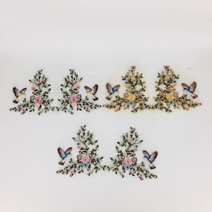 May include: Five embroidered floral appliques with birds. Each applique features a cluster of pink, yellow, and white flowers with green leaves and a small blue bird flying above.