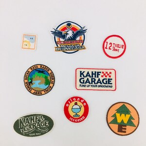 Op de afbeelding: Een verzameling geborduurde patches met verschillende ontwerpen. Eén patch toont een adelaar met de tekst "Teen Crime Mission Remaja Bernegara." Andere patches zijn onder meer "12 Twelve Seas", "KAHF GARAGE" en een patch met een boom en de letter "W".