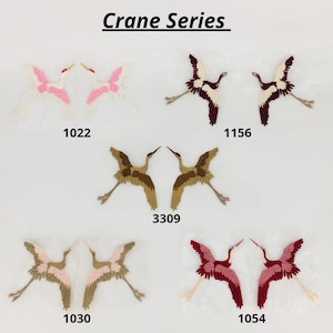 May include: Crane Series embroidery patches in a variety of colours, including white, pink, brown, and red. The patches feature a crane design with a long neck and outstretched wings. The numbers 1022, 1156, 3309, 1030, and 1054 are printed below each patch.