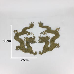 May include: Two gold embroidered dragon patches, each measuring 22 cm wide and 33 cm tall. The dragons face each other with their tails curled.