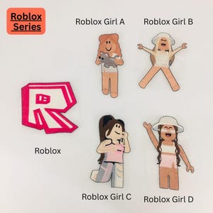 May include: A collection of Roblox-themed fabric patches. The patches include the Roblox logo, four different Roblox girl characters, and the text "Roblox Series". The patches are in various colors, including pink, white, and tan.