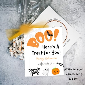 以下が含まれることがあります： オレンジと黒のハロウィーンをテーマにしたグラフィックが描かれた白いカード。カードには「BOO! Here's a Treat For You! Happy Halloween! Brenda & Liz」と書かれており、クモ、幽霊、カボチャのグラフィックが描かれている。カードには「Write in your names with a pen!!」という手書きのメモがある。