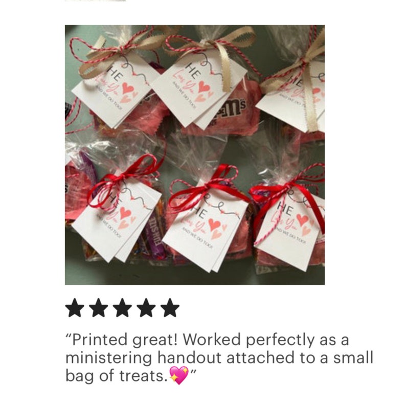 Puede incluir: Un conjunto de peque&ntilde;as bolsas de celof&aacute;n transparentes llenas de caramelos y atadas con una cinta roja. Cada bolsa tiene una peque&ntilde;a etiqueta blanca adjunta con el texto "HE Loves You and We Do Too!" impreso en rosa y negro.